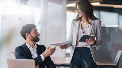 Smiling secretary brought the documents to the boss to sign after meeting