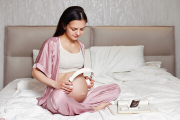 Obraz na płótnie Canvas pregnant woman holding headphones on her belly