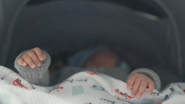 Close up of babies hands while he is sleeping in stroller