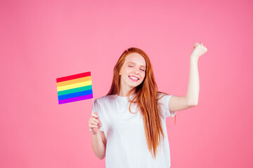 redhaired ginger woman holding colorful flag in studio pink background