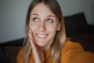 Girl taking selfies, smiling with her hand near her face and looking away