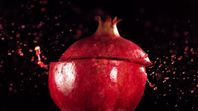 Half Pomegranate falling and splashing on black background. Food levitation concept. Slow Motion