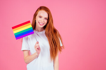 redhaired ginger woman holding colorful flag in studio pink background