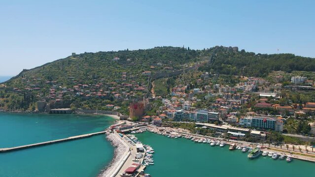 Awesome aerial view of Alanya Marina, the Kizil Kule (Red Tower) and the Tersane (shipyard) in Alanya, Turkey. Drone flying over the coast. Alanya is a popular tourist destination in Turkey.
