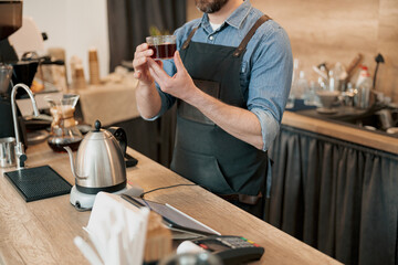 Close up of barista holds a glass of fragrant filter coffee in his hands