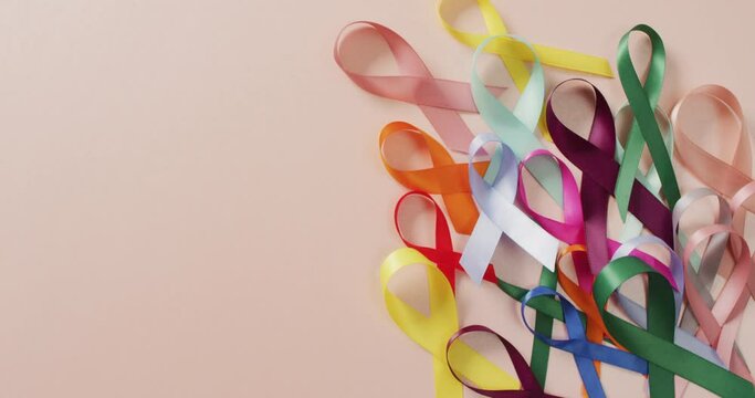Video of colourful cancer ribbons on pale pink background