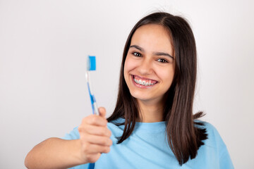 Portrait of a happy teen girl with braces holding a toothbrush smiling.