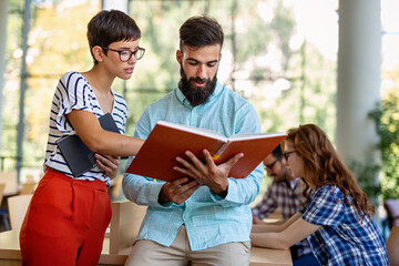 Happy university students studying with books in library. Group of multiracial people in college