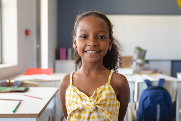 Portrait of smiling african american elementary schoolgirl standing in classroom