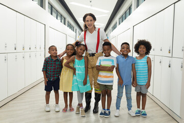 Portrait of african american students with young female caucasian teacher standing in corridor