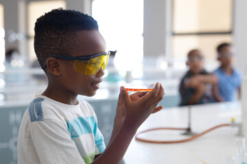 African american elementary schoolboy performing scientific experiment during chemistry class