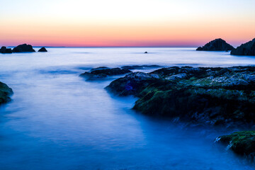 Misty sea water over rocks in sunset