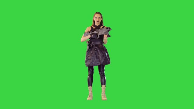 Girl in black tank top and leather skirt stands holding a machine gun on a Green Screen, Chroma Key.
