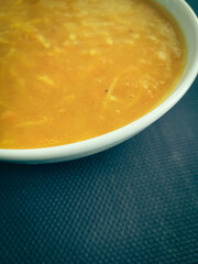 Soupe avec des vermicelles dans un bol blanc sur un fond bleu 