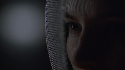 Extreme close up portrait of female fencer in a protective mask, preparing for the fight - Powered by Adobe