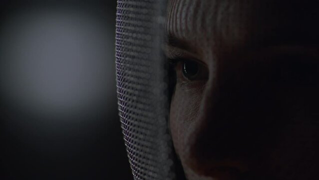 Extreme close up portrait of female fencer in a protective mask, preparing for the fight