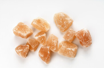 Pink stones of himalayan salt on surface, on white background close-up