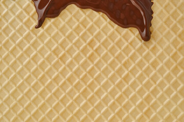 Streams of molten chocolate flowing down a waffle sheet. Close up of the waffle sheet. Pattern wafle texture. Shallow depth of field