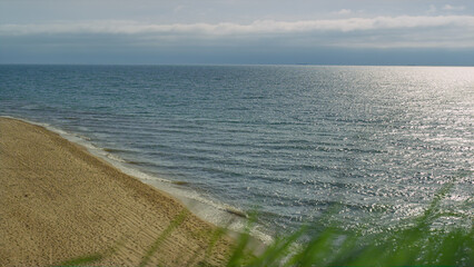 Aerial view empty beach sea shore. Grass blowing wind by crashing ocean waves.