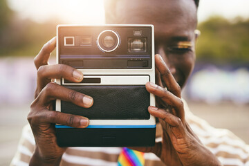 Young gay african man using vintage old camera outdoor - Focus on hands