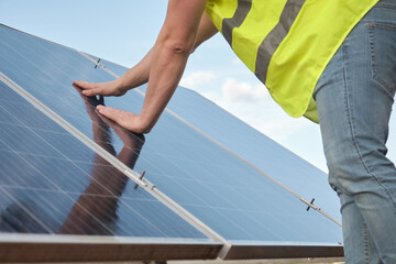 Close up of an engineer checking an operation and cleanliness of solar panels photovoltaic station.