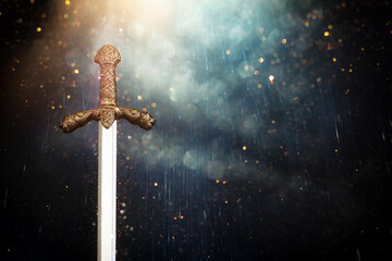 photo of knight sword over dark background. Medieval period concept - obrazy, fototapety, plakaty