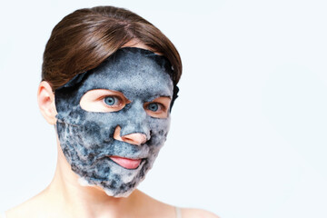 Portrait of a young woman in black bubble mask close-up on white background, copy space.