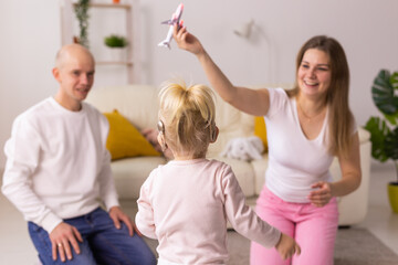 Cochlear implant on the child girl head and playing with mother and father. Hearing aid and deafness and innovative health technology concept - obrazy, fototapety, plakaty