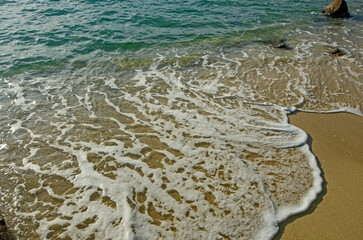 Beautiful white bubbles of waves on yellow sand beach