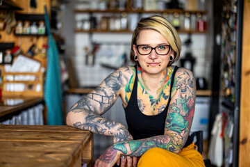 Portrait of an young tattooed woman in a wheelchair at home

