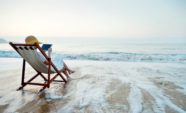 Young woman holding digital tablet at the beach.