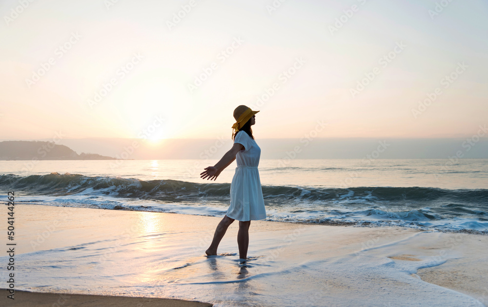 Wall mural happy woman standing on the beach with hands up.