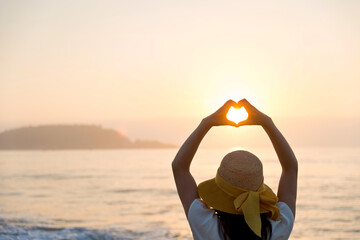 Silhouette hand in heart shape at sunset sky background.