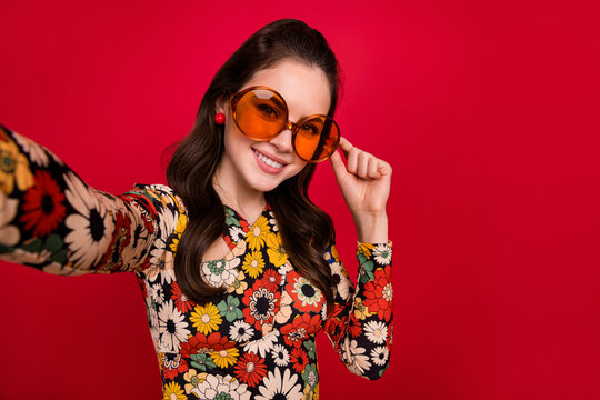 Slef portrait of attractive cheerful girly girl touching specs blogging influencer isolated over bright red color background