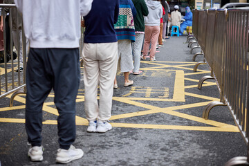 Group of people waiting in line queued far apart to maintain social distance to receive nucleic...