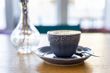 Morning cup of coffee on the background of the window in the backlight of natural sunlight.