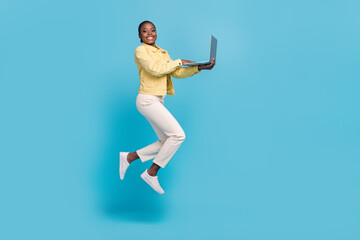 Full length body size view of beautiful trendy cheerful girl jumping using laptop isolated on...