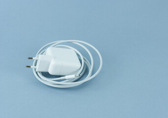 A charger for a tablet on a blue background. Phone charger.
