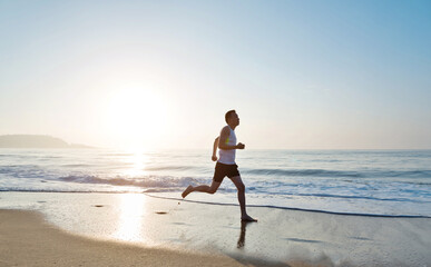 Young man running along beach  in the morning