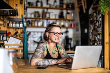 Tattooed woman in wheelchair working on laptop at home
