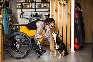 Young woman in wheelchair with her dog at home

