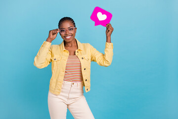 Portrait of attractive cheerful girl holding in hand pink like card answer isolated over bright blue color background