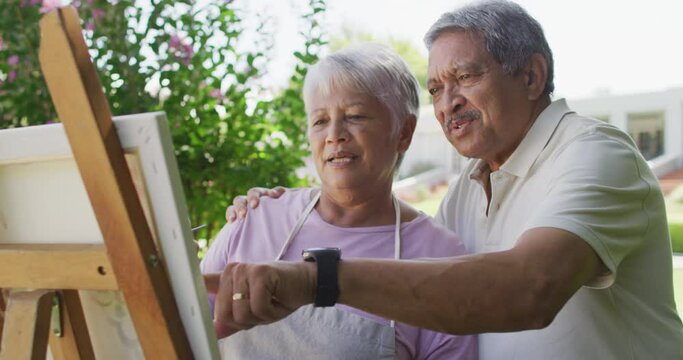 Video of happy biracial senior couple painting in garden