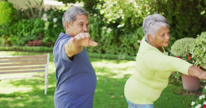 Video of relaxed biracial senior couple practicing yoga in garden