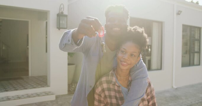 Video of happy african american couple embracing and showing keys to new house