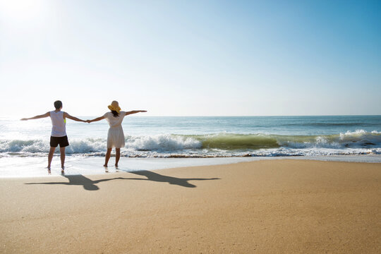 Young couple embracing enjoying ocean on beach.