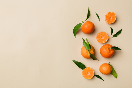Many fresh ripe mandarin with green leaves on colored background, top view, space for text