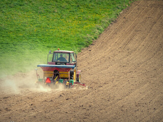 Farm tractor with sowing machine working in the arable field