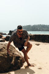 Moda męska letnia, mężczyzna model w koszuli na tle skał. © insomniafoto