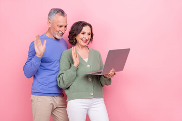 Portrait of two cheerful people arms palm wave hi wireless netbook isolated on pink color background